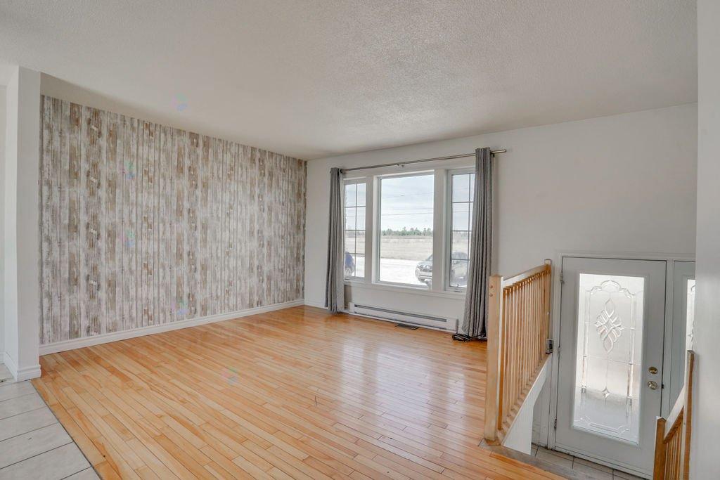 A room with wooden floors and a large window with a view of the outside.