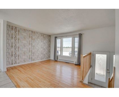 A room with wooden floors and a large window with a view of the outside.