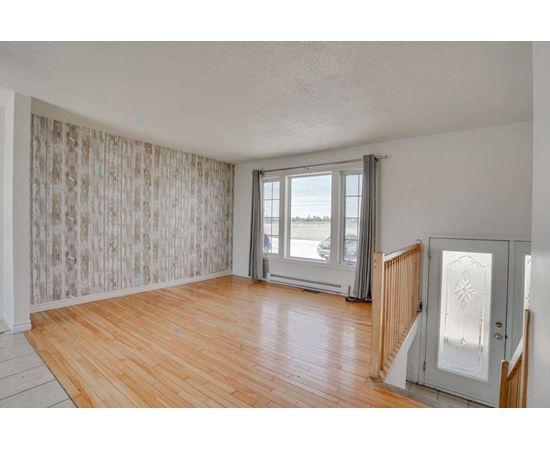 A room with wooden floors and a large window with a view of the outside.