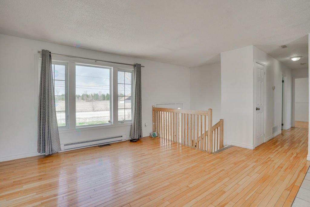 A room with wooden floors and a window with curtains.