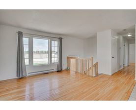 A room with wooden floors and a window with curtains.
