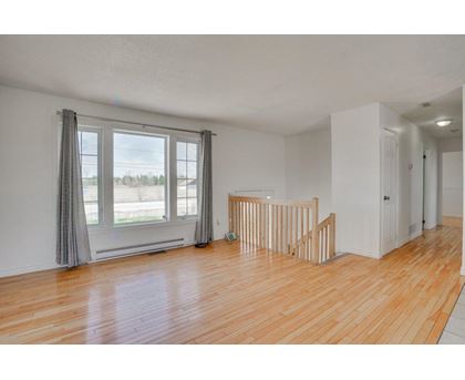 A room with wooden floors and a window with curtains.