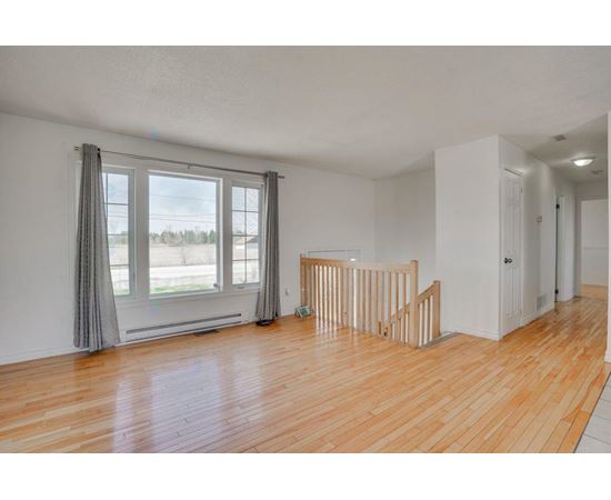 A room with wooden floors and a window with curtains.