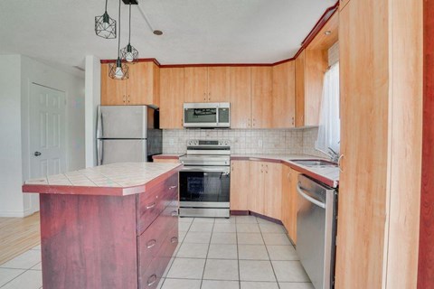 A kitchen with wooden cabinets and a red island.