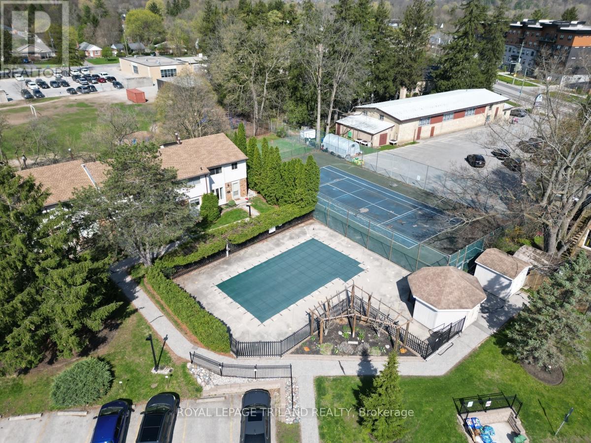 An aerial view of a tennis court surrounded by a fence and a building in the background.