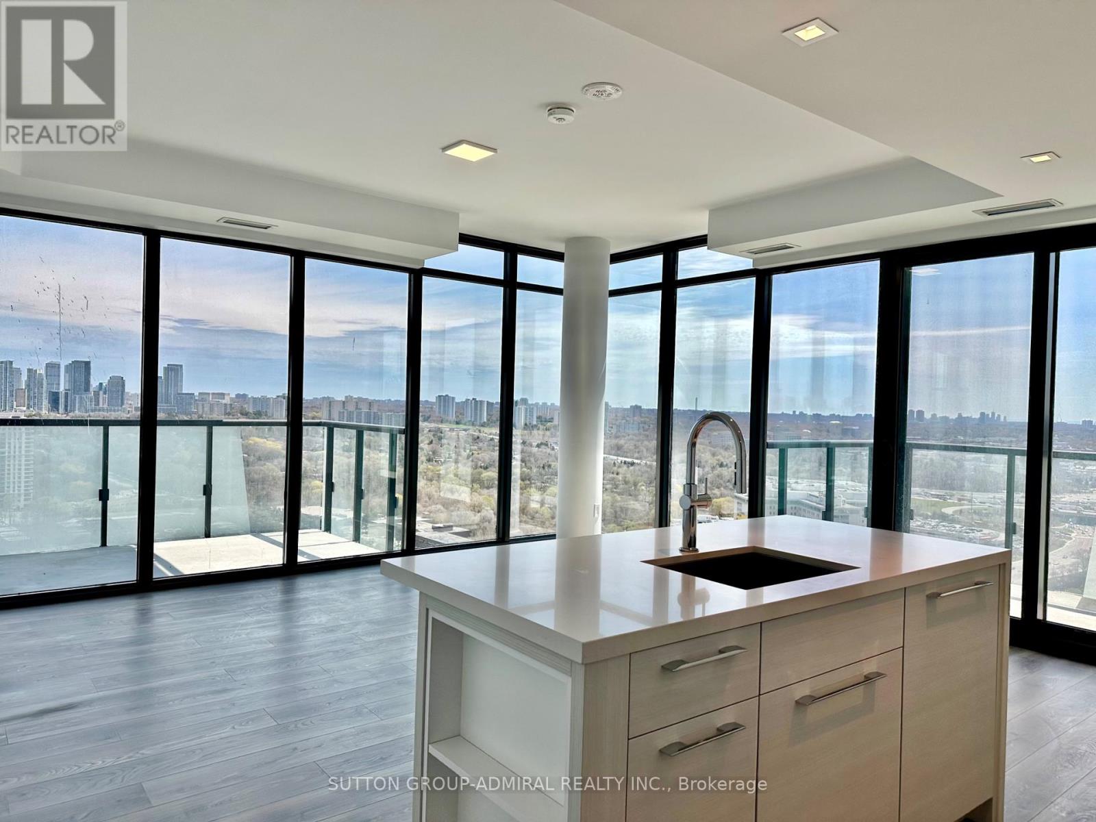 A modern kitchen with a view of the cityscape outside the large windows.