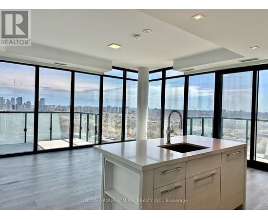 A modern kitchen with a view of the cityscape outside the large windows.
