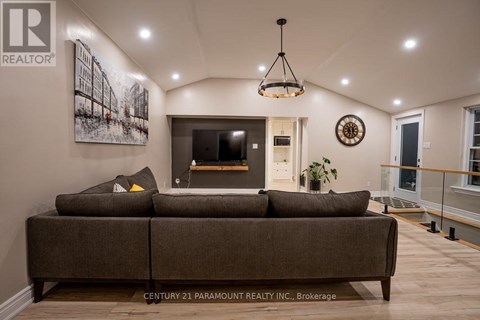 A living room with a brown couch and a painting on the wall.