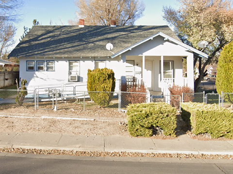 A white house with a black roof and a small front porch.