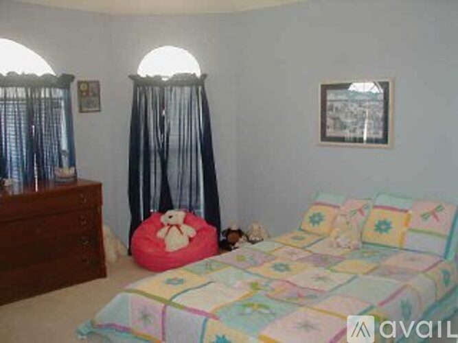 A bedroom with a bed, a dresser, and a window with curtains.