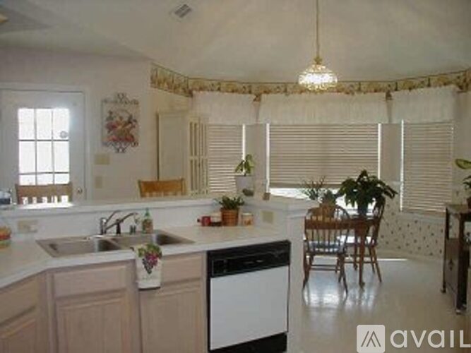A kitchen with a sink, dishwasher, and a table with chairs.