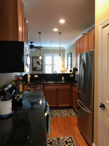 A kitchen with a black counter top and wooden cabinets.