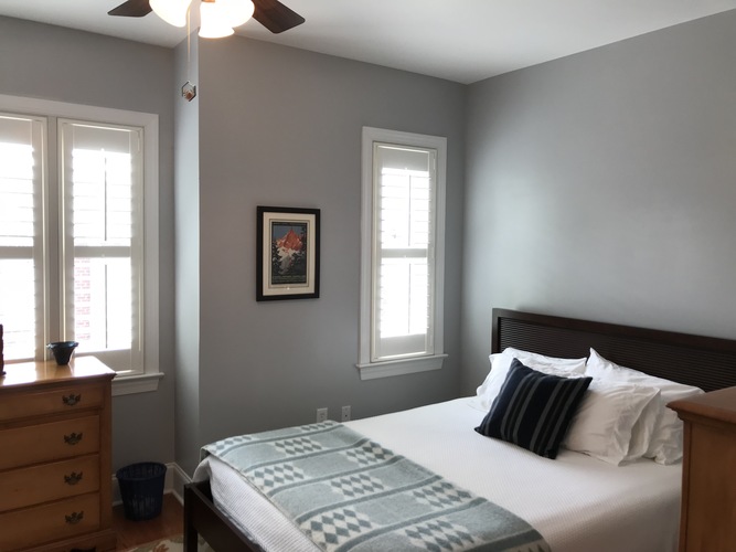 A bedroom with a bed, dresser, and window.