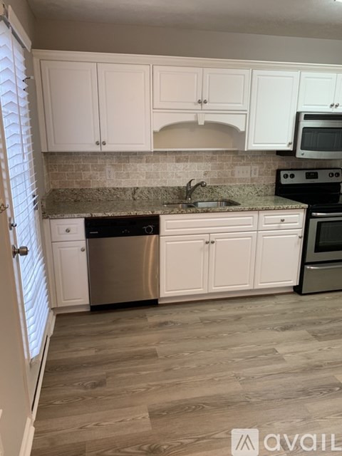 A kitchen with white cabinets and a stainless steel dishwasher.