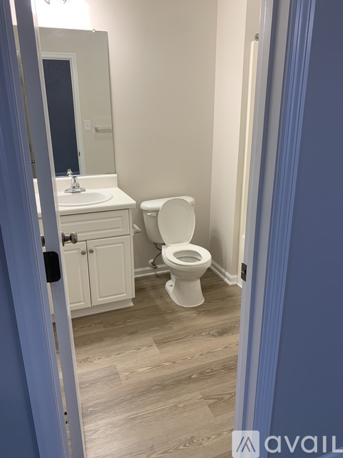 A white toilet in a bathroom with a white cabinet and a mirror above the sink.