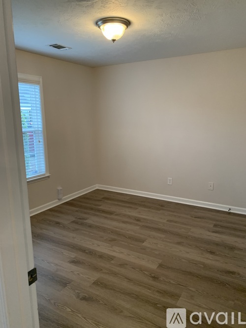 A room with wooden flooring and a window.