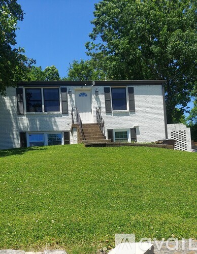 A two-story house with a white exterior and a green lawn in front.