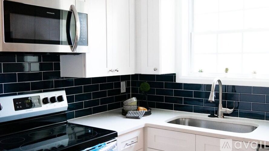 A kitchen with a black stove top oven and a white microwave above it.