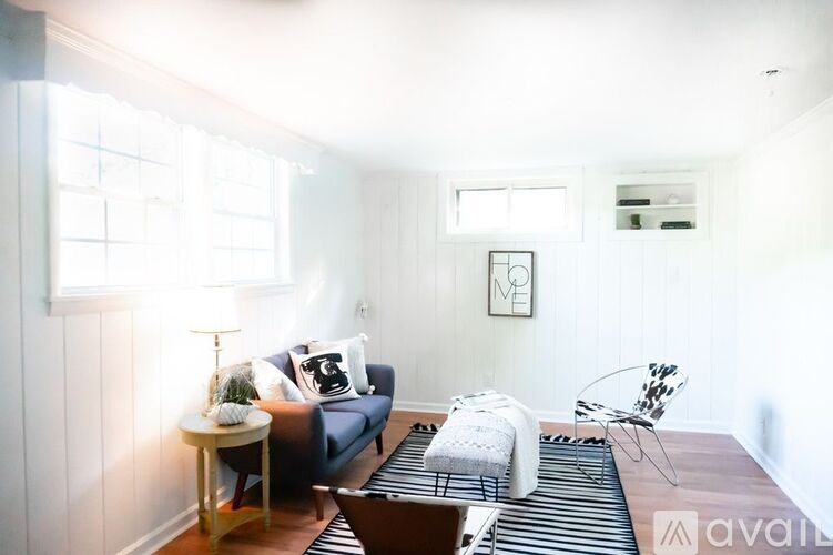 A living room with a blue couch, a white chair, and a small table with a plant on it.