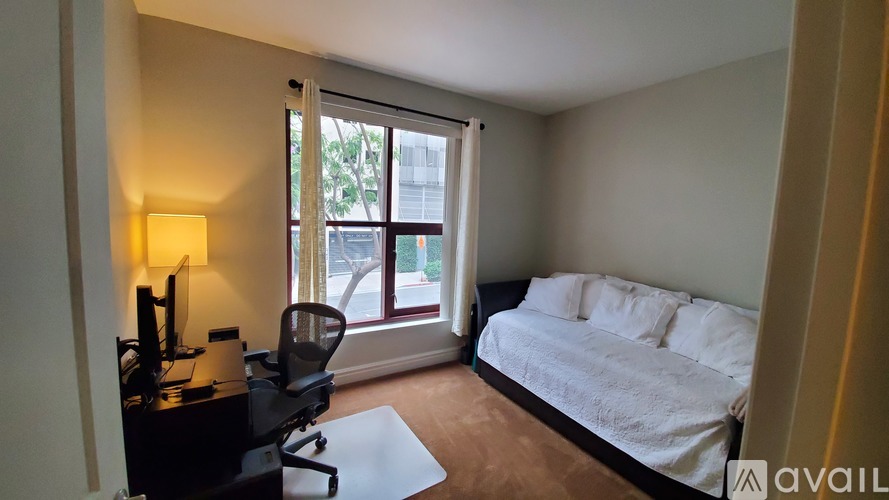 A bedroom with a bed, desk, chair, and window.