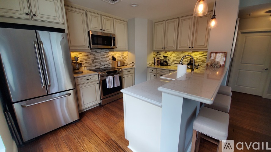 A kitchen with a stainless steel refrigerator and a white island.