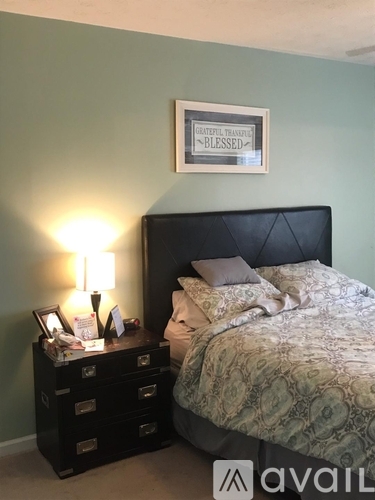 A bedroom with a bed, nightstand, and a picture frame on the wall.