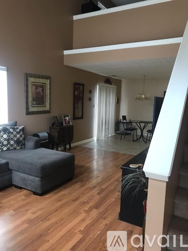 A living room with a grey ottoman and a white couch.