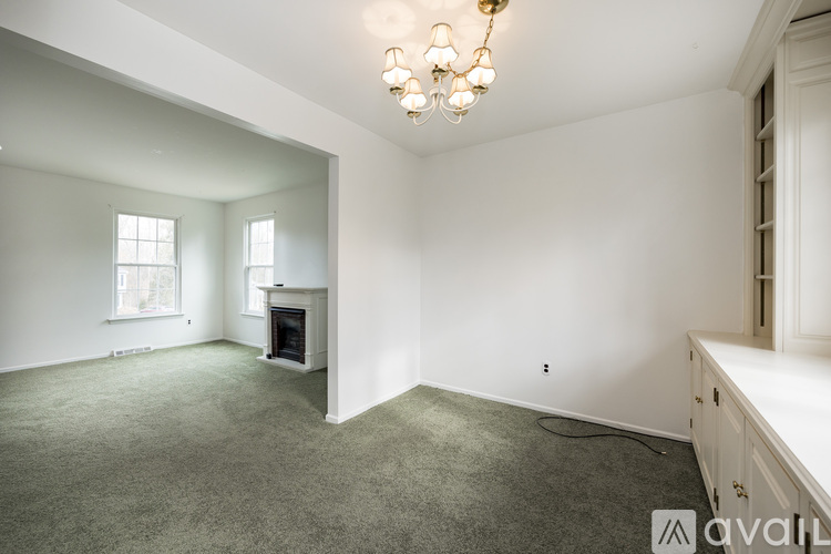 A spacious living room with a fireplace and a chandelier.