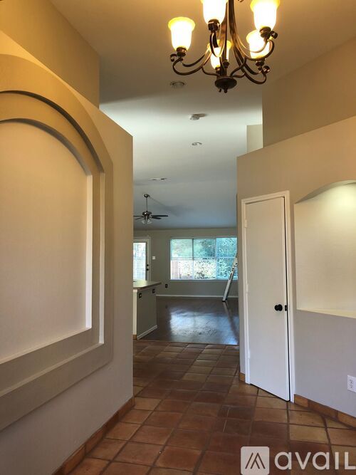 A hallway with a chandelier and a door on the right.