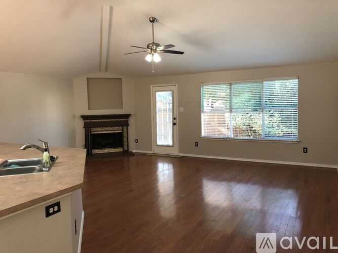 A living room with a fireplace and a kitchen area with a sink.