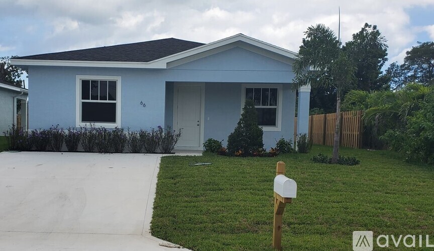 A blue house with a white fence and a mailbox in front.