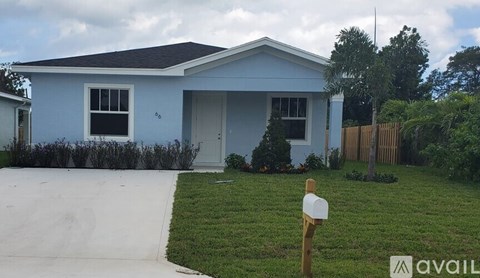 A blue house with a white fence and a mailbox in front.