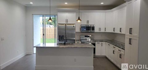 A kitchen with white cabinets and a large island.