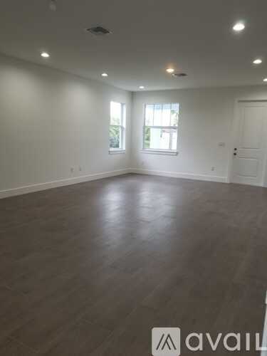 A spacious room with wooden flooring and a window letting in natural light.