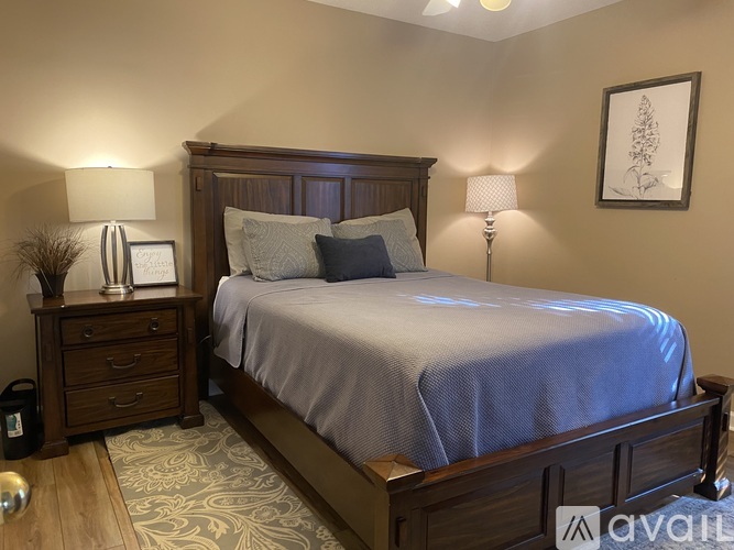 A bedroom with a bed, nightstand, and lamps.