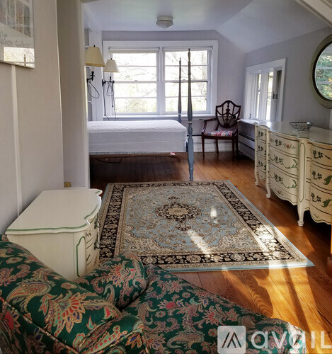 A bedroom with a bed, dresser, and window.