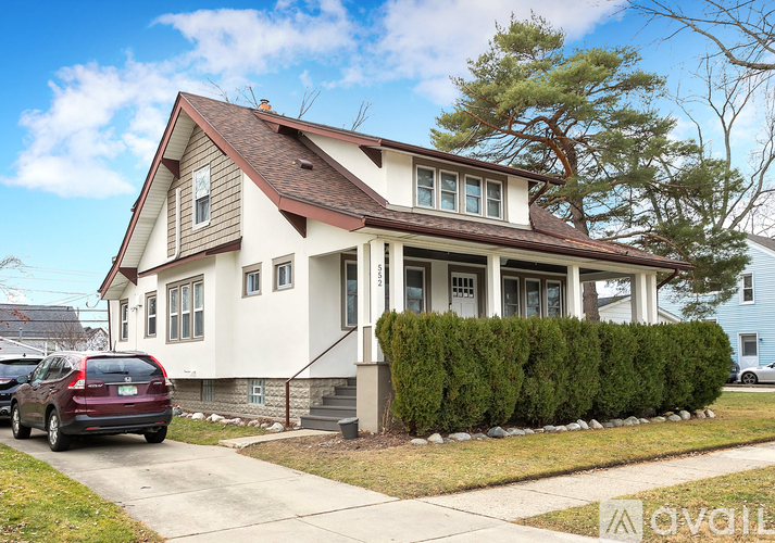 A two-story house with a white exterior and a brown roof.