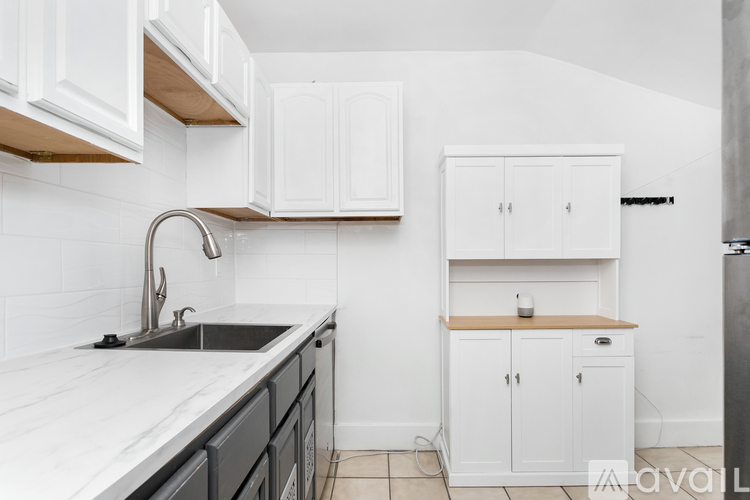 A kitchen with white cabinets and a marble countertop.