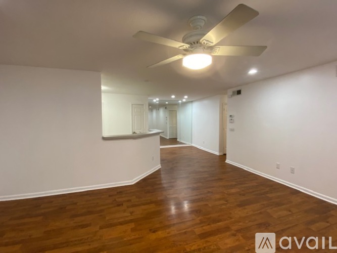 A spacious room with wooden floors and a ceiling fan.