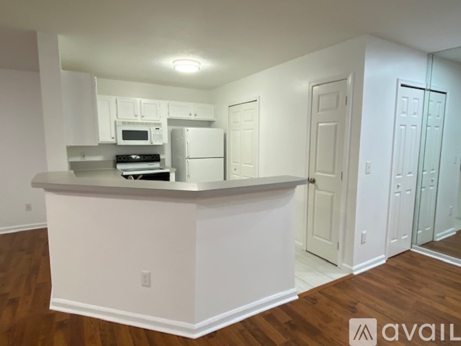 A white kitchen with a bar counter and a refrigerator.