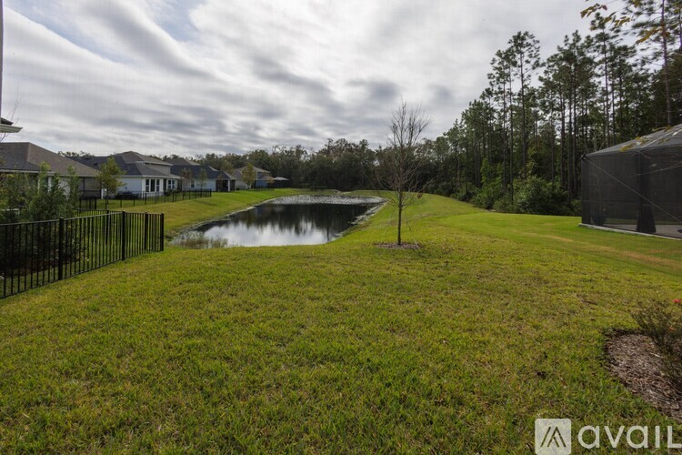 A grassy area with a pond and a house in the background.