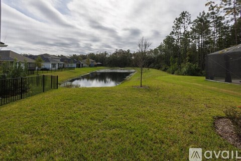 A grassy area with a pond and a house in the background.