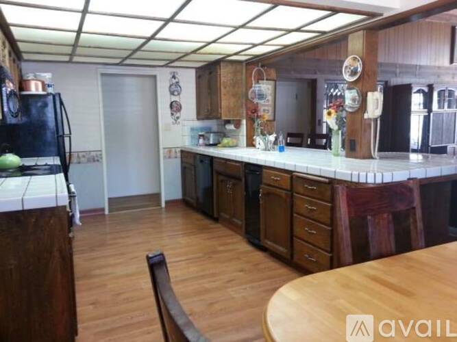 A kitchen with wooden floors and a table in the middle.
