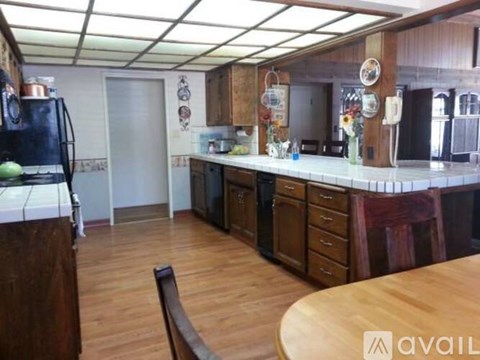 A kitchen with wooden floors and a table in the middle.