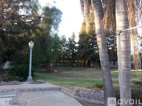 A street lamp stands in a park with trees and grass.