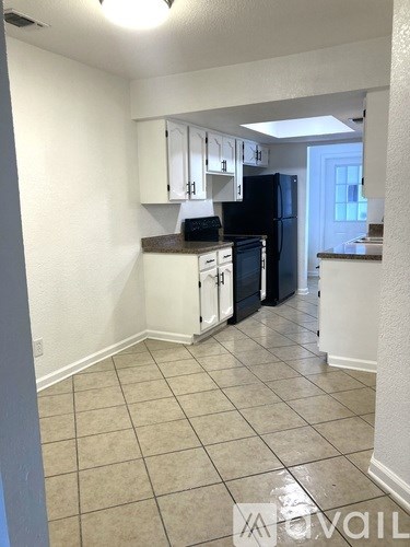 A kitchen with white cabinets and black appliances.