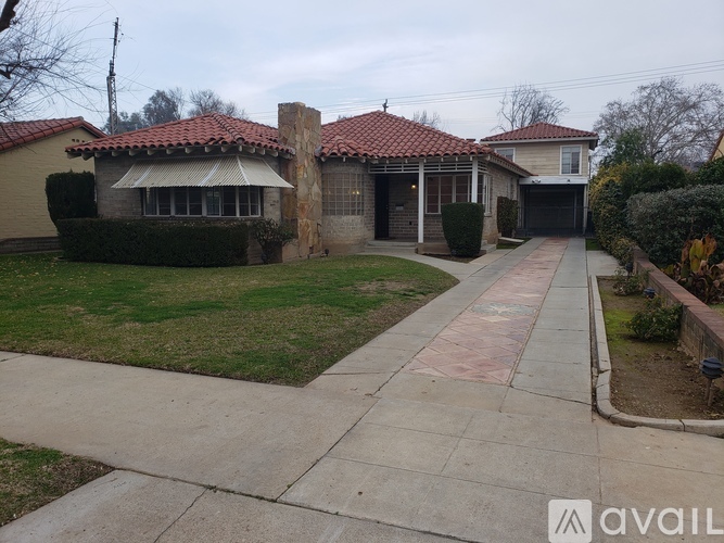 A house with a red tile roof and a stone pillar in the front yard.