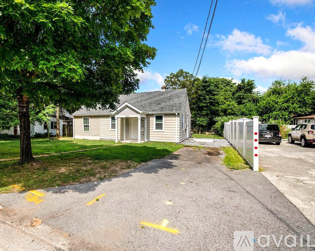 A house with a driveway and a tree in front of it.