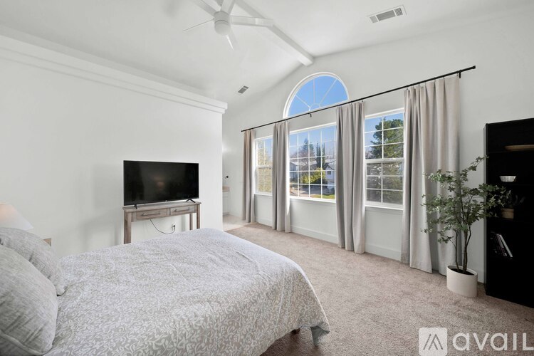 A bedroom with a large bed and a television on a stand.