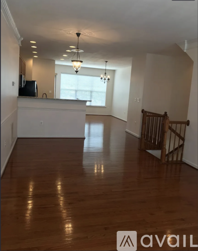 A spacious room with wooden floors and a chandelier.